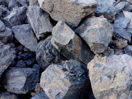 Textura de carbón negro en grandes piedras. Se vierten grandes cantidades de carbón en una pila. El tema de los recursos naturales y la minería y sus antecedentes.