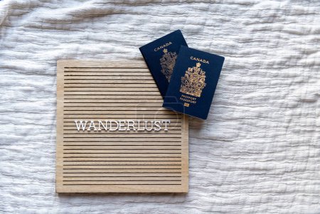 Foto de Palabra errante en un tablero de madera beige con letras blancas con pasaportes canadienses - Imagen libre de derechos