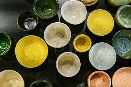 Flay lay Komposition von Tisch voller unterschiedlicher Farben Formen und Größen handgemachte gefleckte Keramik Tassen Schalen