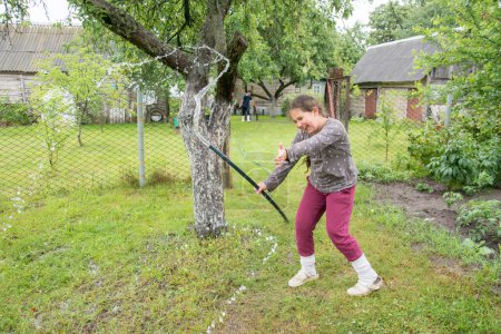Téléchargez les photos : Dans l'après-midi d'été dans le jardin, une fille joue avec un tuyau et de l'eau. - en image libre de droit