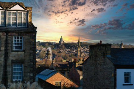 Téléchargez les photos : Coucher de soleil pittoresque sur un paysage urbain historique avec des bâtiments en silhouette et des nuages spectaculaires à Lancaster. - en image libre de droit