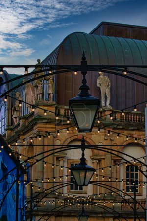 Téléchargez les photos : Vue au crépuscule d'un bâtiment classique avec un lampadaire au premier plan et des lumières décoratives, évoquant une scène urbaine romantique à Harrogate, en Angleterre. - en image libre de droit
