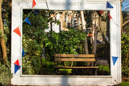 Quaint garden bench framed by a wooden pergola with hanging colorful bunting in Harrogate.
