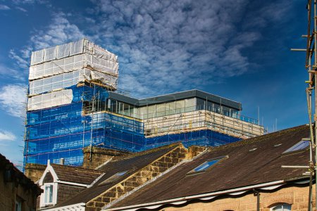 Building under construction with scaffolding against a blue sky with clouds in Harrogate, England.