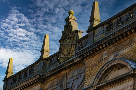 Historic building facade with ornate sculptures against a blue sky with clouds in Harrogate, England.