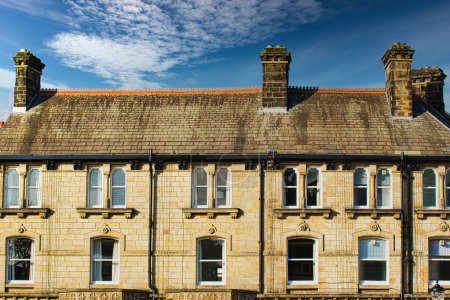 Traditional brick row houses under blue sky with wispy clouds in Harrogate, England.