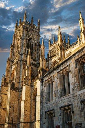 Gotische Kathedrale vor einem dramatischen Himmel bei Sonnenuntergang mit komplexer Architektur und historischer Pracht in York, Großbritannien.