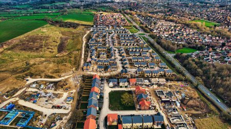 Luftaufnahme einer vorstädtischen Wohnsiedlung mit unvollendetem Bau, Straßen und grünen Feldern in Harrogate, North Yorkshire.