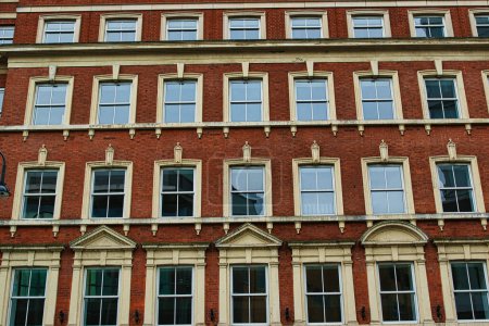 Façade d'un bâtiment classique en brique rouge avec des fenêtres symétriques contre un ciel clair à Leeds, Royaume-Uni.