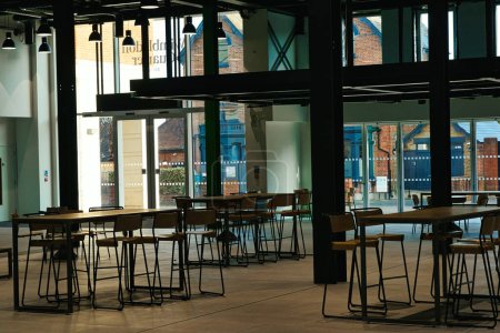 Modernes Café-Interieur mit leeren Tischen und Stühlen, großen Fenstern und Stadtblick.