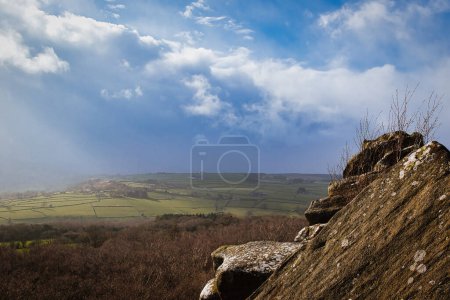 Scenic view from a rocky outcrop overlooking a lush valley under a dramatic cloudy sky at Brimham Rocks, in North Yorkshire