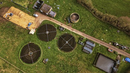 Vue aérienne d'une ferme rurale avec des champs de cultures circulaires, un chemin de terre et du matériel agricole dans le Yorkshire du Nord.