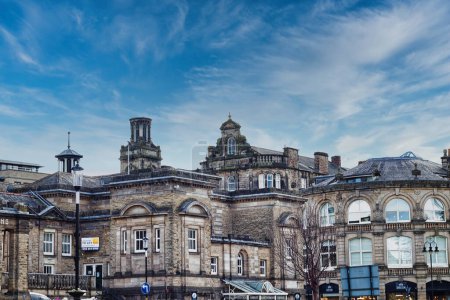 Klassisch europäische Architektur unter einem dynamischen Himmel mit wehenden Wolken und historischen Gebäuden mit komplexen Fassaden in einer urbanen Umgebung in Harrogate, North Yorkshire.