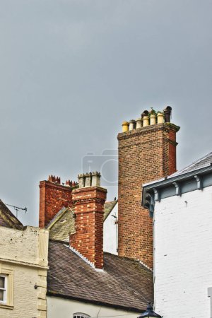 Ornate brick chimneys on historic buildings against a cloudy sky, showcasing architectural details and textures.