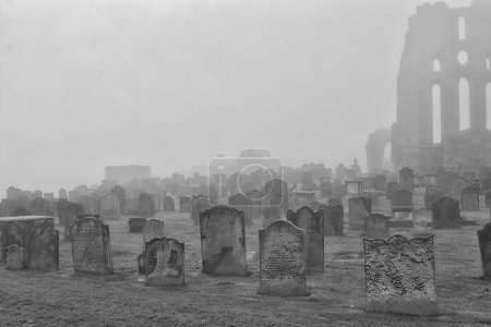 A foggy cemetery with numerous old tombstones and a partially visible ancient ruin in the background.