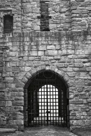 Black and white photo of a medieval stone gate with a portcullis.