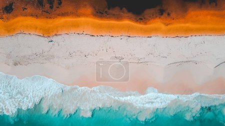 Aerial view of where the river meets the sea. Vibrant orange and dark river meet turquoise sea waves on beach in Western Australian town called Guilderton. Seascape background. Coastal wallpaper.