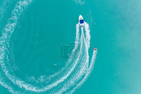 Luftaufnahme von Schnellboot auf türkisfarbenem Meer an einem sonnigen Tag. Schnelle Yacht auf dem Ozean. Seelandschaft von einer Drohne aus. Seelandschaft aus der Luft. Lebendige helle sonnige Tag im Sommer Tapete. Hintergrund: das Meer. Küstentapete.