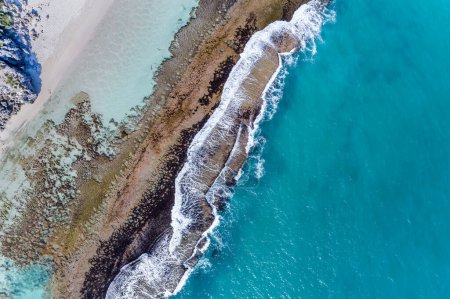 Foto de Vista aérea al mar paisaje marino de verano hermosas olas, arrecife de agua azul en el día soleado. Vista superior desde el dron. Increíble fondo de naturaleza tropical. Hermosas olas de mar brillantes salpicando en la arena de playa. Arrecife de Yanchep, Australia Occidental. - Imagen libre de derechos