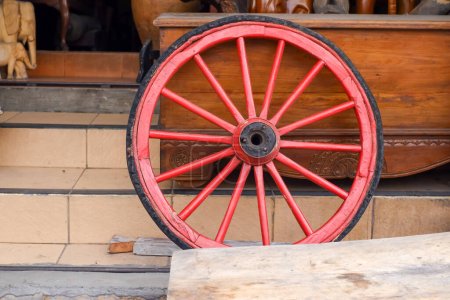 Old red wooden cart wheels on display in front of an antique shop