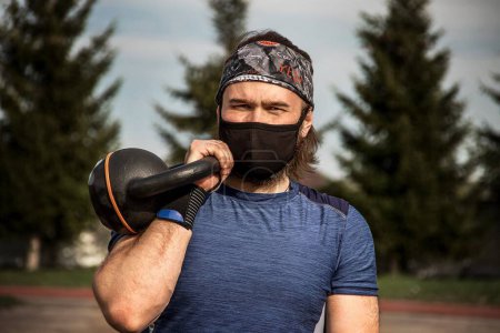 Photo for Muscular bearded male athlete workout outdoor with kettlebell we - Royalty Free Image