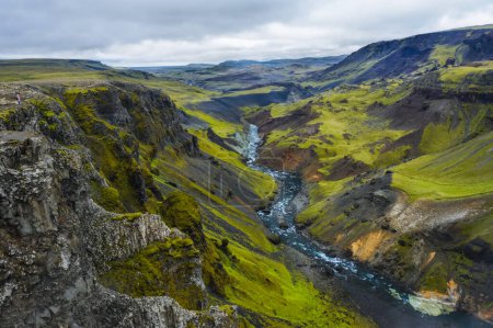 Foto de Senderista disfrutando de Highlands of Iceland. Río Fossa arroyo en el valle del cañón Landmannalaugar. Las colinas y los acantilados están cubiertos de musgo verde. - Imagen libre de derechos