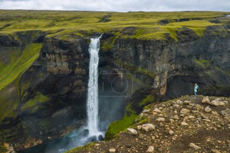 Téléchargez les photos : Vue aérienne de la femme avec sac à dos profitant de la cascade Haifoss des Highlands d'Islande. - en image libre de droit
