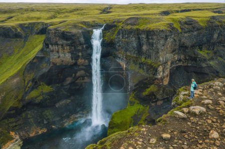 Téléchargez les photos : Vue aérienne de la femme avec sac à dos profitant de la cascade Haifoss des Highlands d'Islande. - en image libre de droit