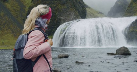 Photo for Iceland, woman with backpack enjoying Stjornarfoss waterfall near Kirkjubaejarklaustur. - Royalty Free Image