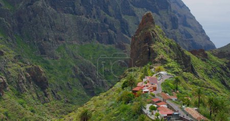 Téléchargez les photos : Masca village, green mountains gorge ravine in Tenerife, Canary Islands, Spain. Sunny day. Touristic famous destination. Cityscape. - en image libre de droit