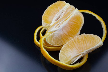 Téléchargez les photos : Une orange pelée, avec la peau disposée autour d'elle, servie sur une assiette, révélant les textures du fruit - en image libre de droit
