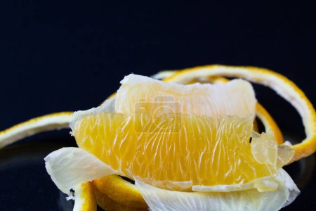 Téléchargez les photos : Une orange pelée, avec la peau disposée autour d'elle, servie sur une assiette, révélant les textures du fruit - en image libre de droit