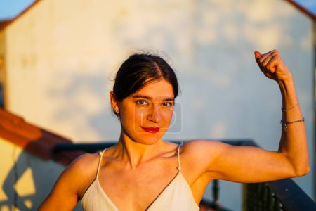 Téléchargez les photos : Jeune fille sportive montrant les muscles en plein air dans une terrasse - en image libre de droit