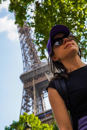 Foto de Niña con gafas de sol caminando frente a la torre Eiffel en ángulo bajo - Imagen libre de derechos