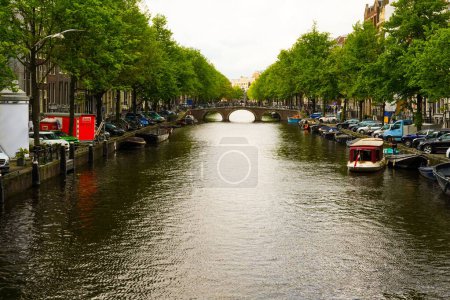 Téléchargez les photos : Canal d'Amsterdam avec quelques bateaux et voitures dans un après-midi nuageux - en image libre de droit