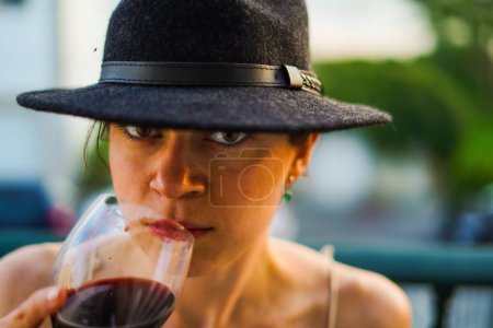 Téléchargez les photos : Jeune fille portant un chapeau noir célébrant en plein air boire du vin - en image libre de droit