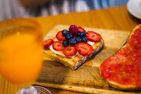 Photo for Tasty complete breakfast with a blueberry and strawberry toast and an orange juice - Royalty Free Image