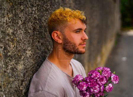 Téléchargez les photos : Jeune homme aux cheveux mi-blonds avec un bouquet de fleurs violettes - en image libre de droit