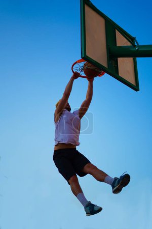 Téléchargez les photos : Homme jouant au basket et plongeant sur le ciel bleu - en image libre de droit