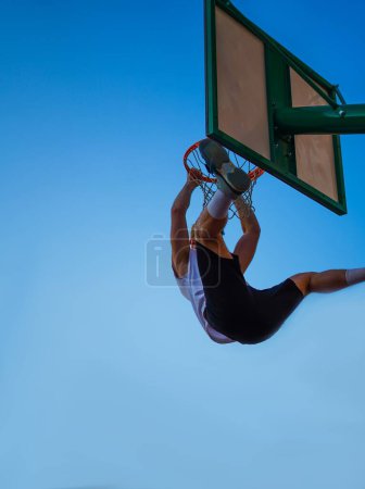 Téléchargez les photos : Homme jouant au basket et faisant un dunk sur le ciel bleu - en image libre de droit