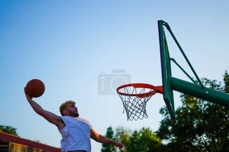 Téléchargez les photos : Homme jouant au basket essayant de faire un dunk d'une main - en image libre de droit