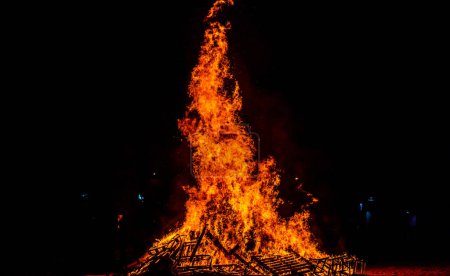 Foto de Quemando leña en la playa en una celebración creando perfectas llamas de fuego - Imagen libre de derechos