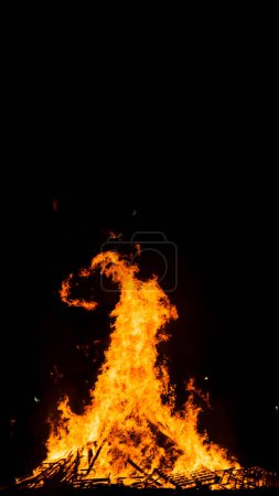 Foto de Gran hoguera en la playa por la noche con formas beatas en las altas llamas - Imagen libre de derechos