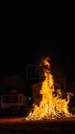 Foto de Celebración rural con la ciudad agujero observando el fuego de una hoguera en la playa por la noche con la lanza de copia - Imagen libre de derechos