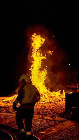 Foto de Bombero salvando un incendio con la manguera en el suelo por la noche - Imagen libre de derechos