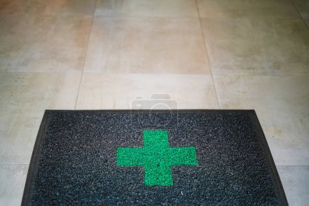 Téléchargez les photos : Tapis de pharmacie à l'entrée de l'entreprise avec une croix verte - en image libre de droit