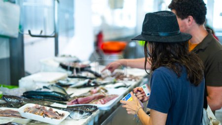 Téléchargez les photos : Couple choisissant un poisson à acheter dans un marché local - en image libre de droit