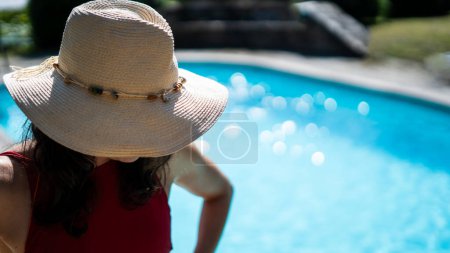 Téléchargez les photos : Femme brune anonyme en maillot de bain rouge à la piscine par une journée ensoleillée. Concept de vacances. - en image libre de droit