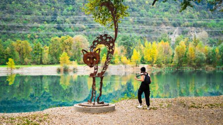 Téléchargez les photos : Sac à dos femme touristique et une sculpture d'un lac de chat en Suisse. - en image libre de droit