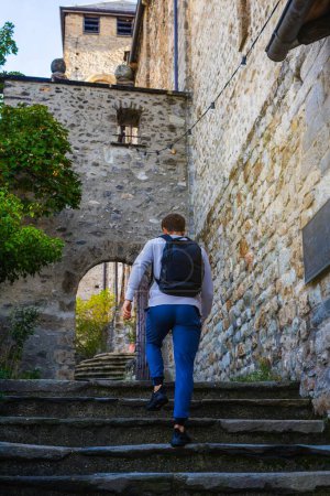 Young man walking up the stairs of a medieval town in a sunny day